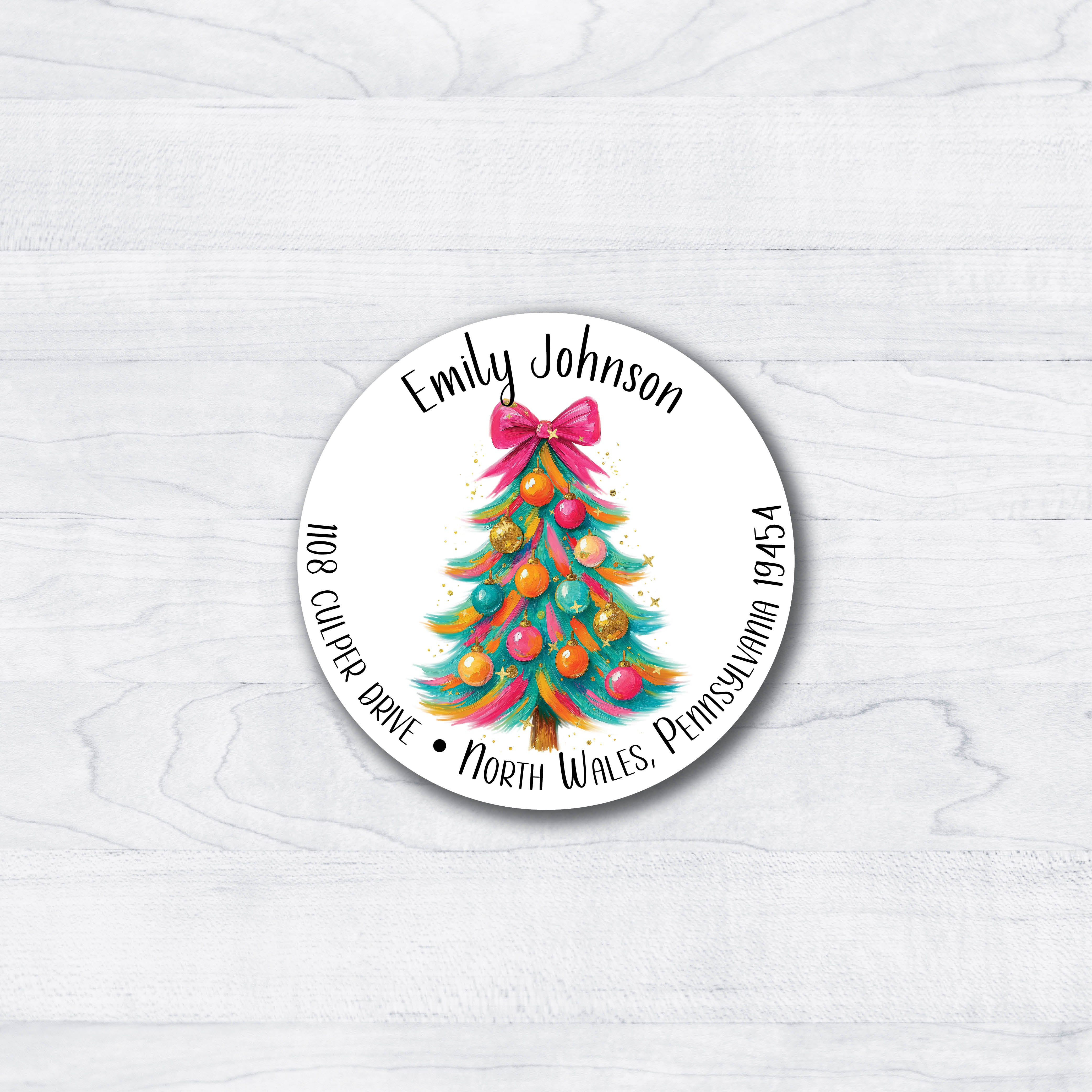 Christmas tree with a pink bow, teals, pinks and yellow decorations on a round return address label