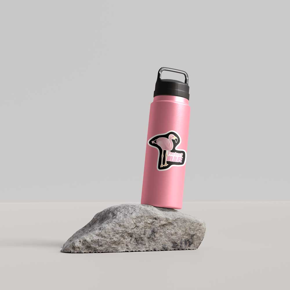 Pink water bottle with a black cap and logo on a gray rock against a light gray background