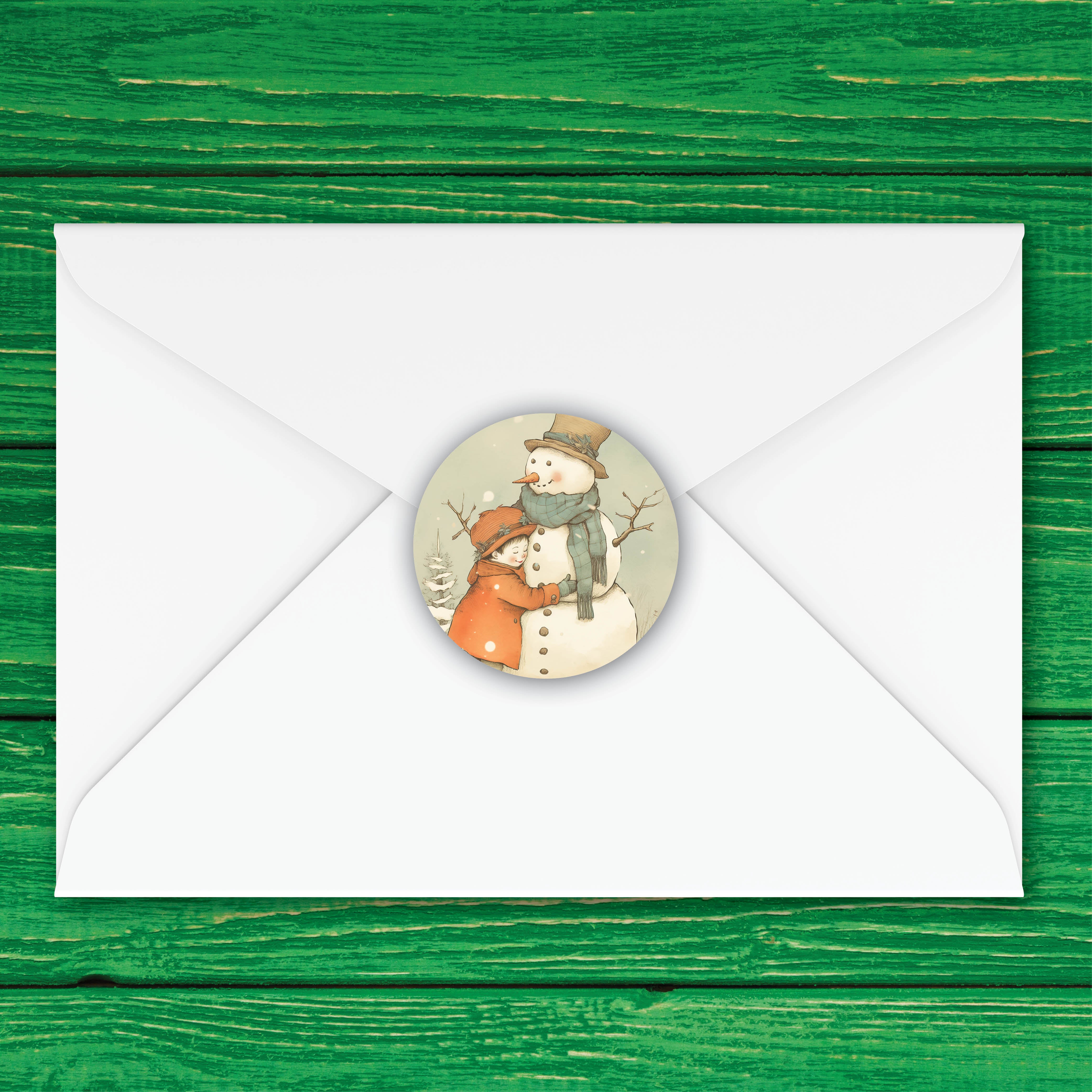 A round illustrated snowman envelope seal displayed on the center of a white envelope, set against a green wooden plank background.